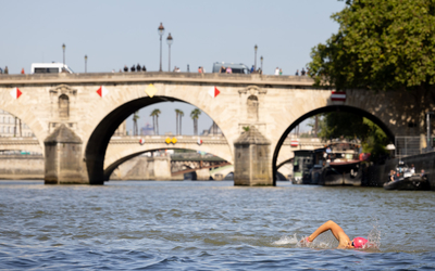Un nageur pratiquant le crawl avec un bonnet rose dans la Seine. 