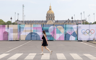 Une femme marchant devant les signalétiques JO dans les rues de Paris. 
