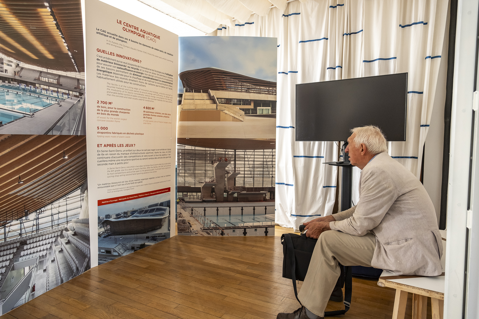 Un visiteur assis devant les panneaux de l'exposition
