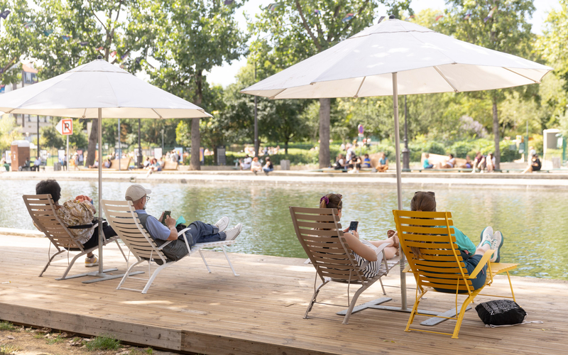 Des personnes se reposent sous les parasols du Repos du canal st Martin.