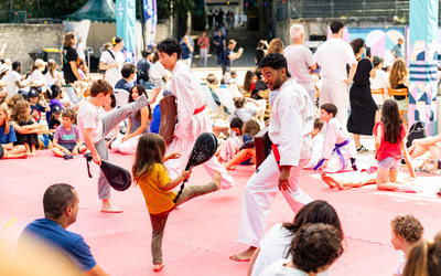 Deux enfants s'entraînent sur des mouvements de karaté auprès de deux adultes en kimono 