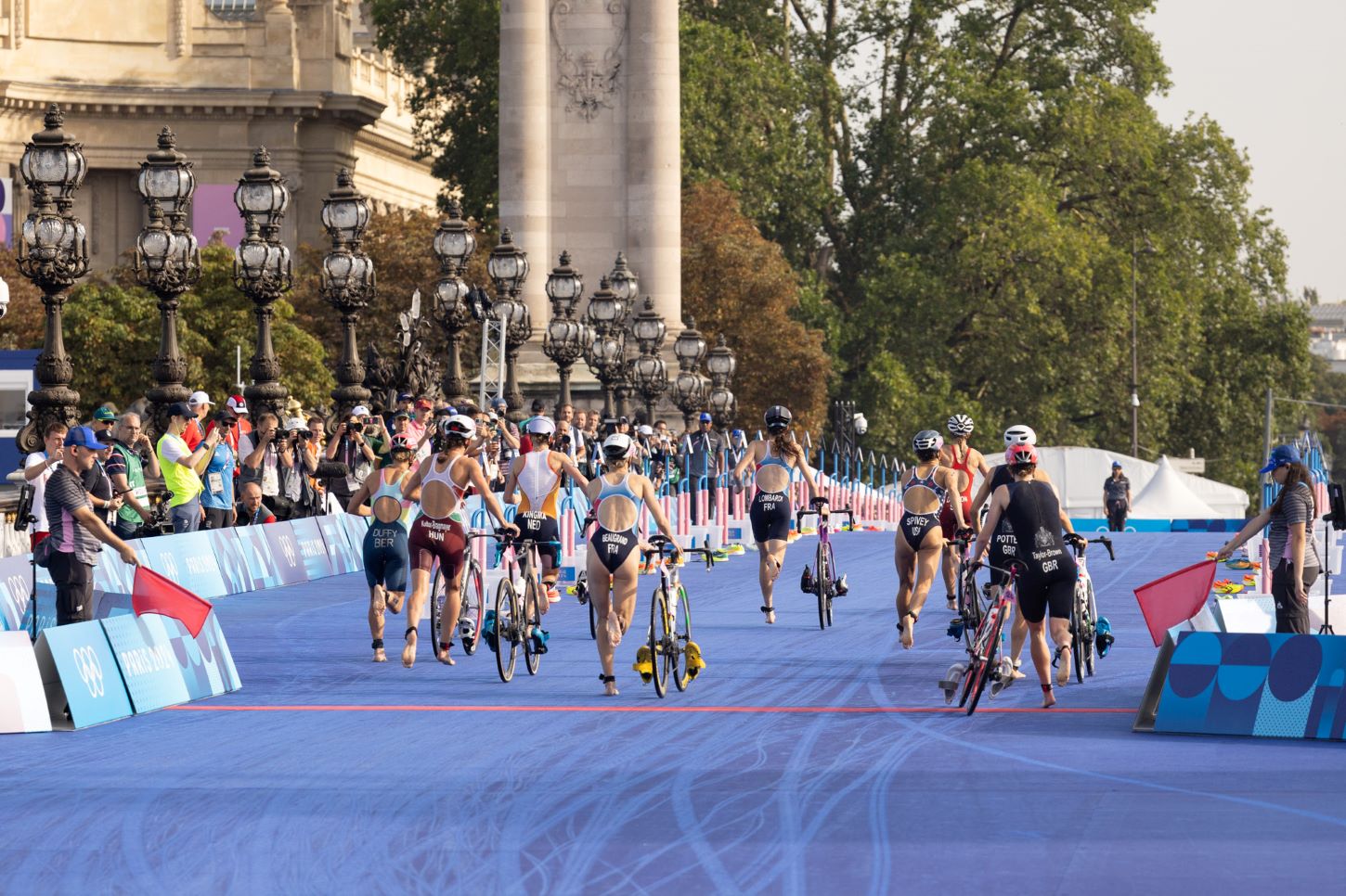 Des triathlètes sur un pont courent à côté de leur vélo