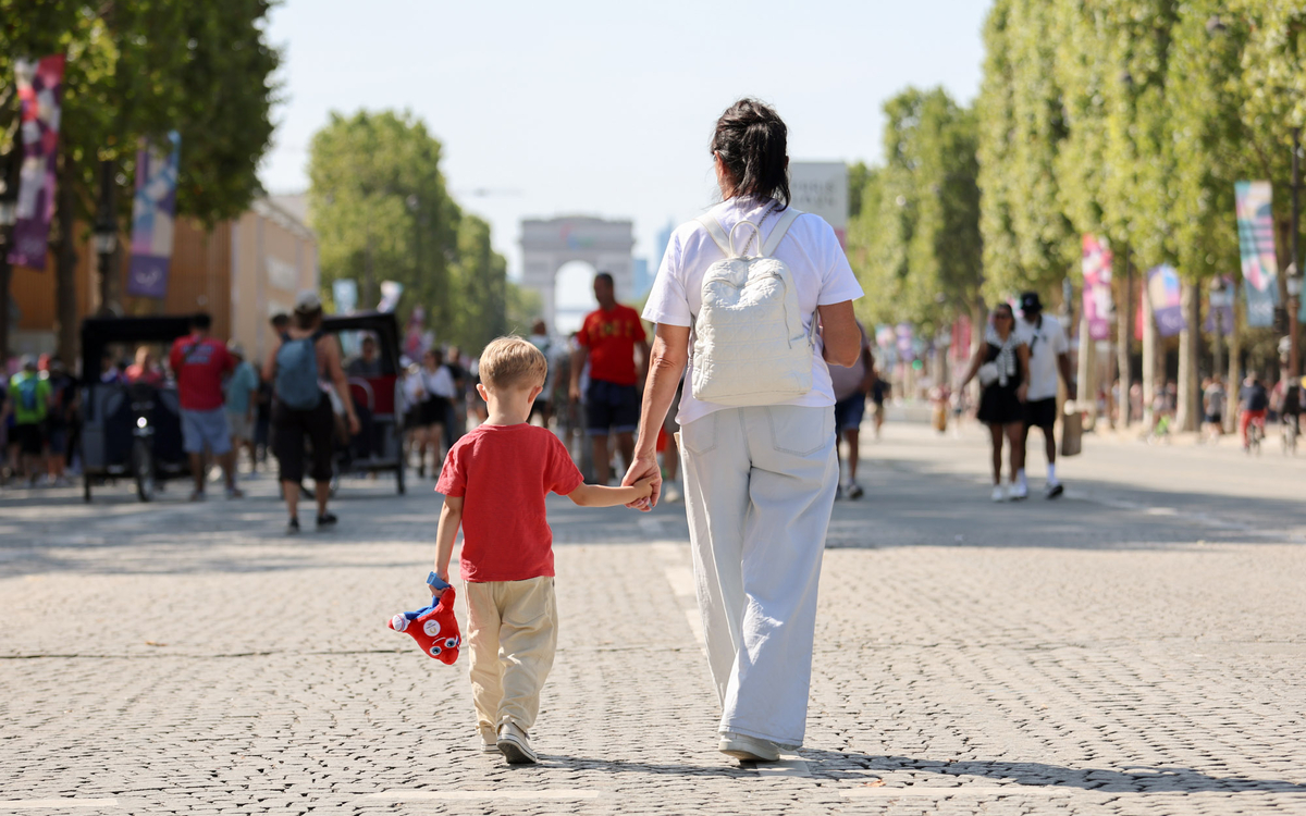 Une femme et un enfant se promenant sur les Champs Elysées en direction de l'Arc de Triomphe.