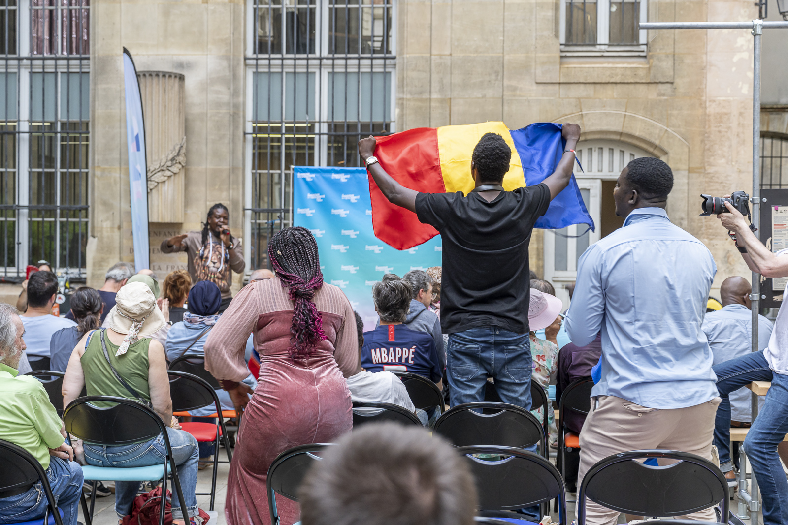 Photo d'un bénévole tenant un drapeau du Tchad lors de la soirée Paris Solidaire a un incroyable talent