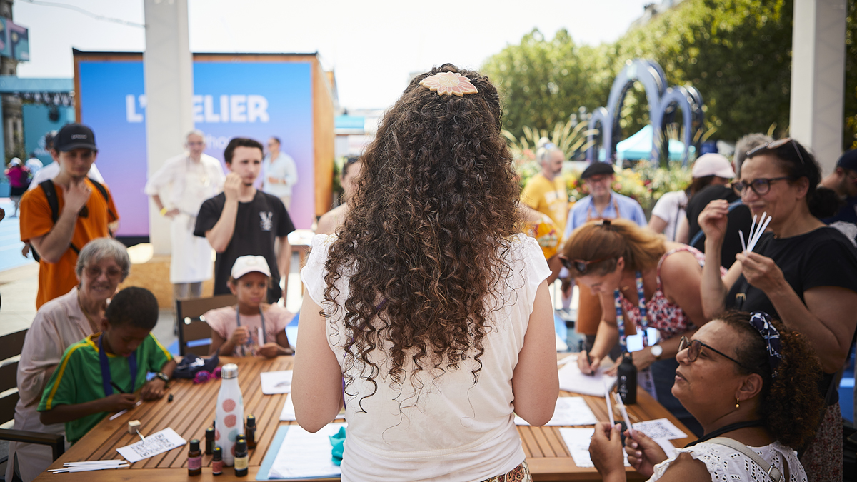 Des participants sentent des fragrances lors d'un atelier olfactif sur la terrasse des jeux. 