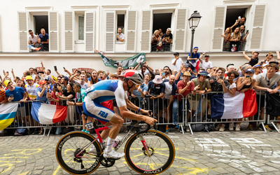 A French cyclist rides past a crowd shouting in support.