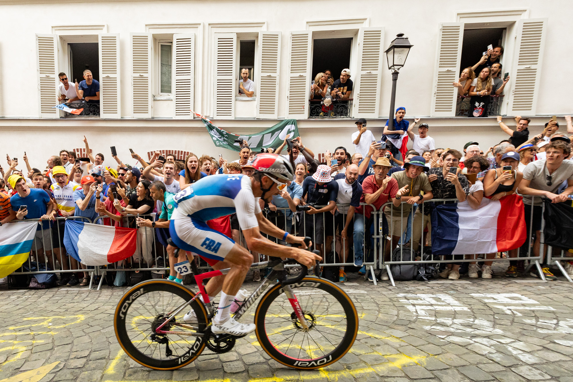A French cyclist rides past a crowd shouting in support.