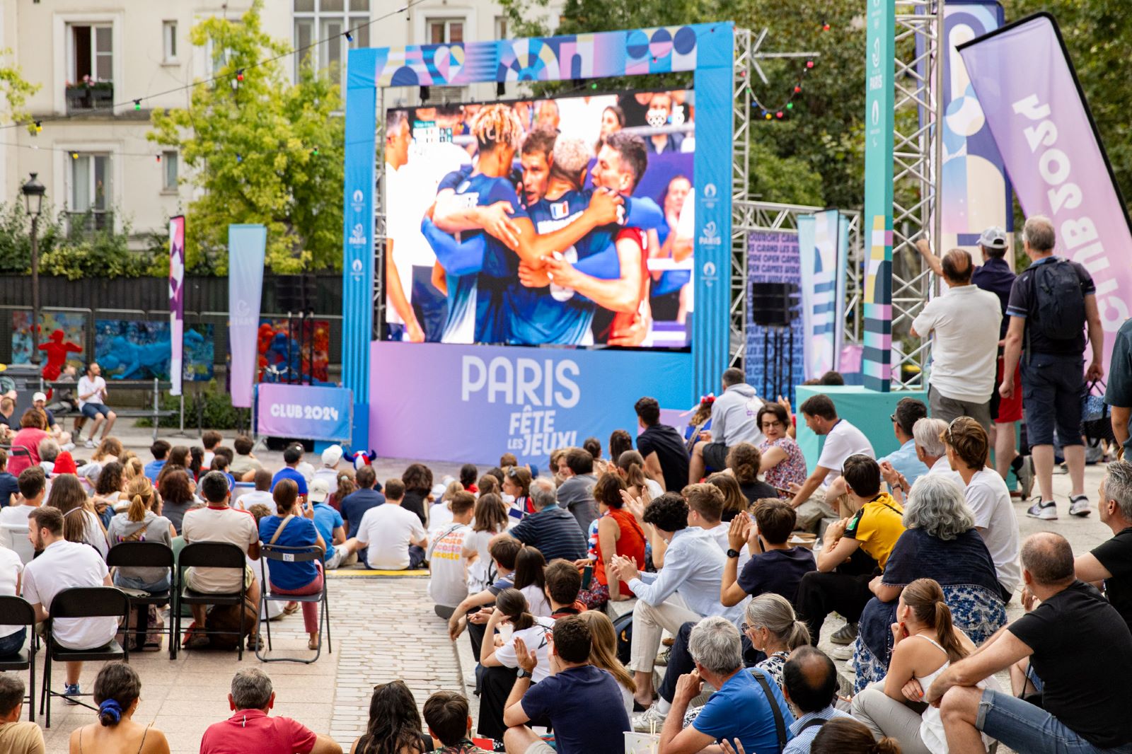 une foule d'individus tournés vers un écran géant qui diffuse un match de volley