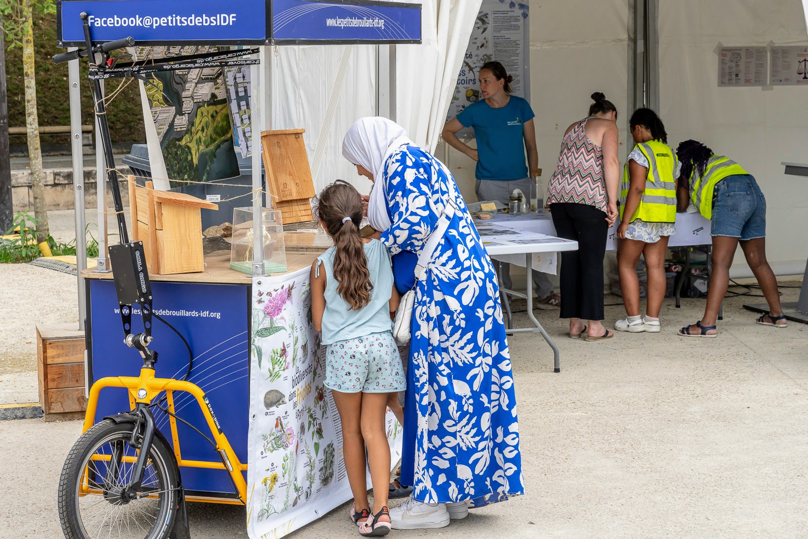 Une mère et sa petite fille observent des papillons séchés sur un stand