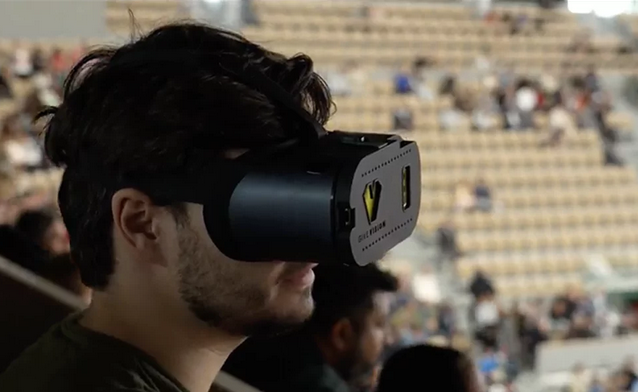 homme portant un télé agrandisseur portatif pour suivre une compétition sportive dans un stade 