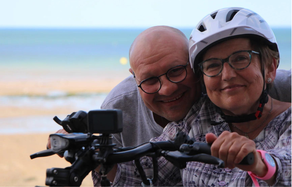 Nicole et Patrick testant une trottinette en fauteuil roulant en bord de mer.