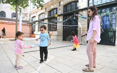 Deux enfants jouent aux raquettes avec leur mère dans la cour de l'école