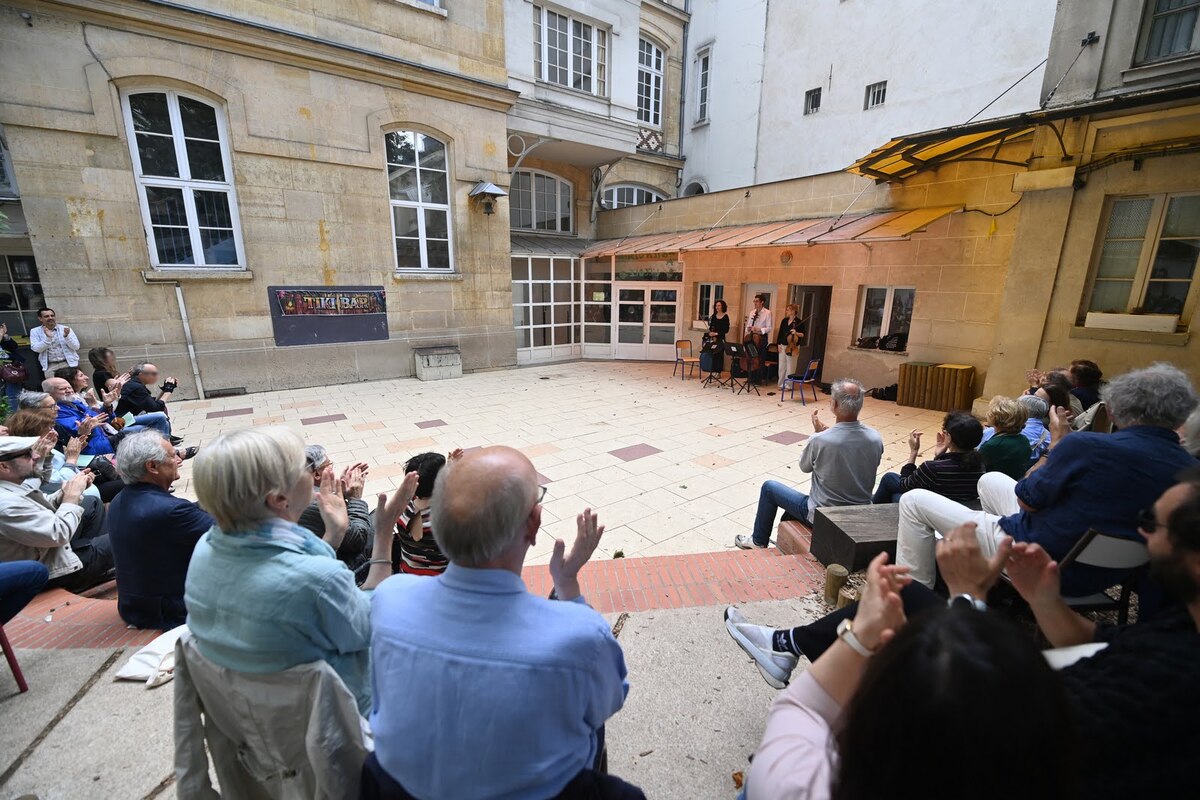 Des spectateurs assis applaudissent les musiciens du trio à cordes