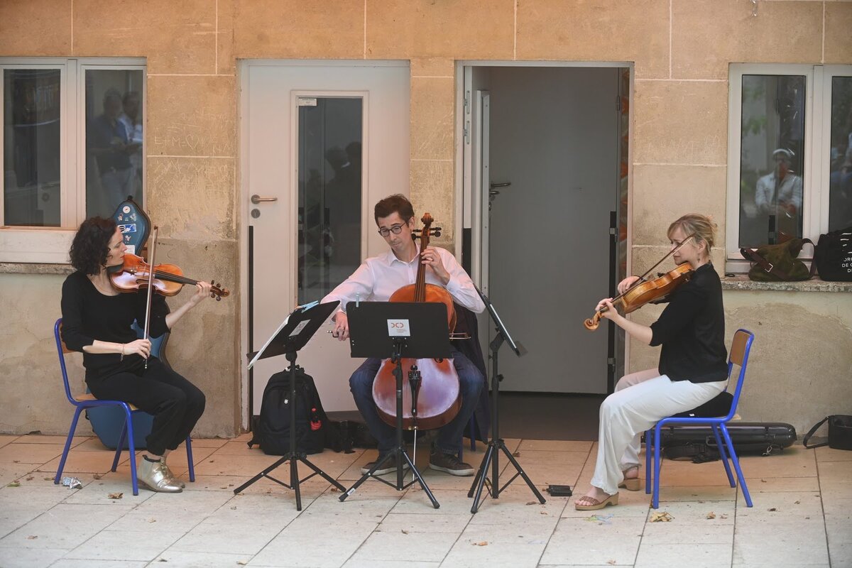 Un trio d'instruments à corde de l'orchestre de chambre de Paris joue dans la cour de l'école Cordier
