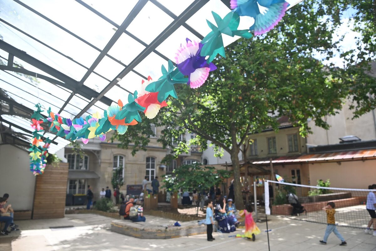 Vue sur la cour ou des adultes assis côtoient des enfants qui jouent