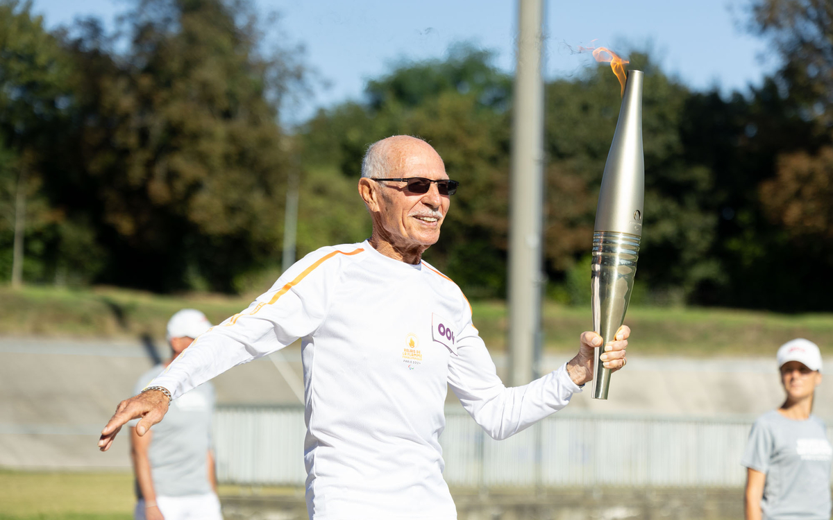 Photo du vétéran cycliste Raymond Pellé avec la Flamme paralympique
