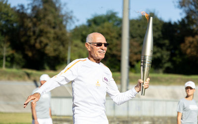 Photo du vétéran cycliste Raymond Pellé avec la Flamme paralympique