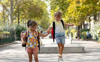 2 enfants avec des lunettes marchent en se tenant la main 