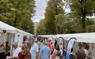 une allée bordée de stand avec des gens qui déambulent 