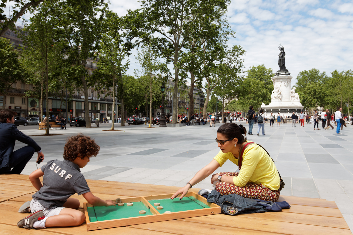 Une femme et un enfant jouent sur l'R de jeux de la place de la République. 