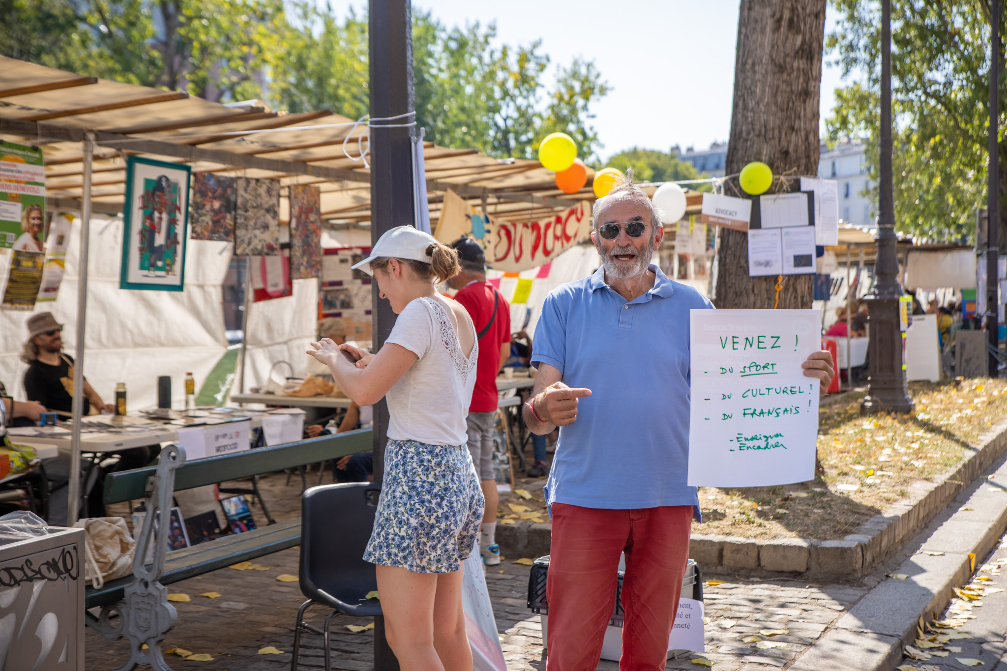 Stands associatifs sur le quai de Valmy, avec un homme qui porte un panneau