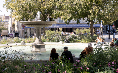 Des personnes sont assises devant la fontaine de la place Pigalle, 9e