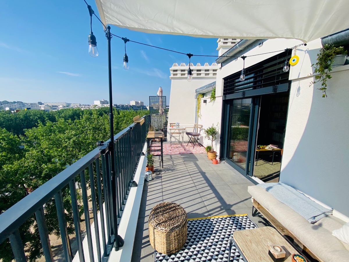 Une terrasse aménagée avec une guirlande, un banc, une table basse et un tabouret
