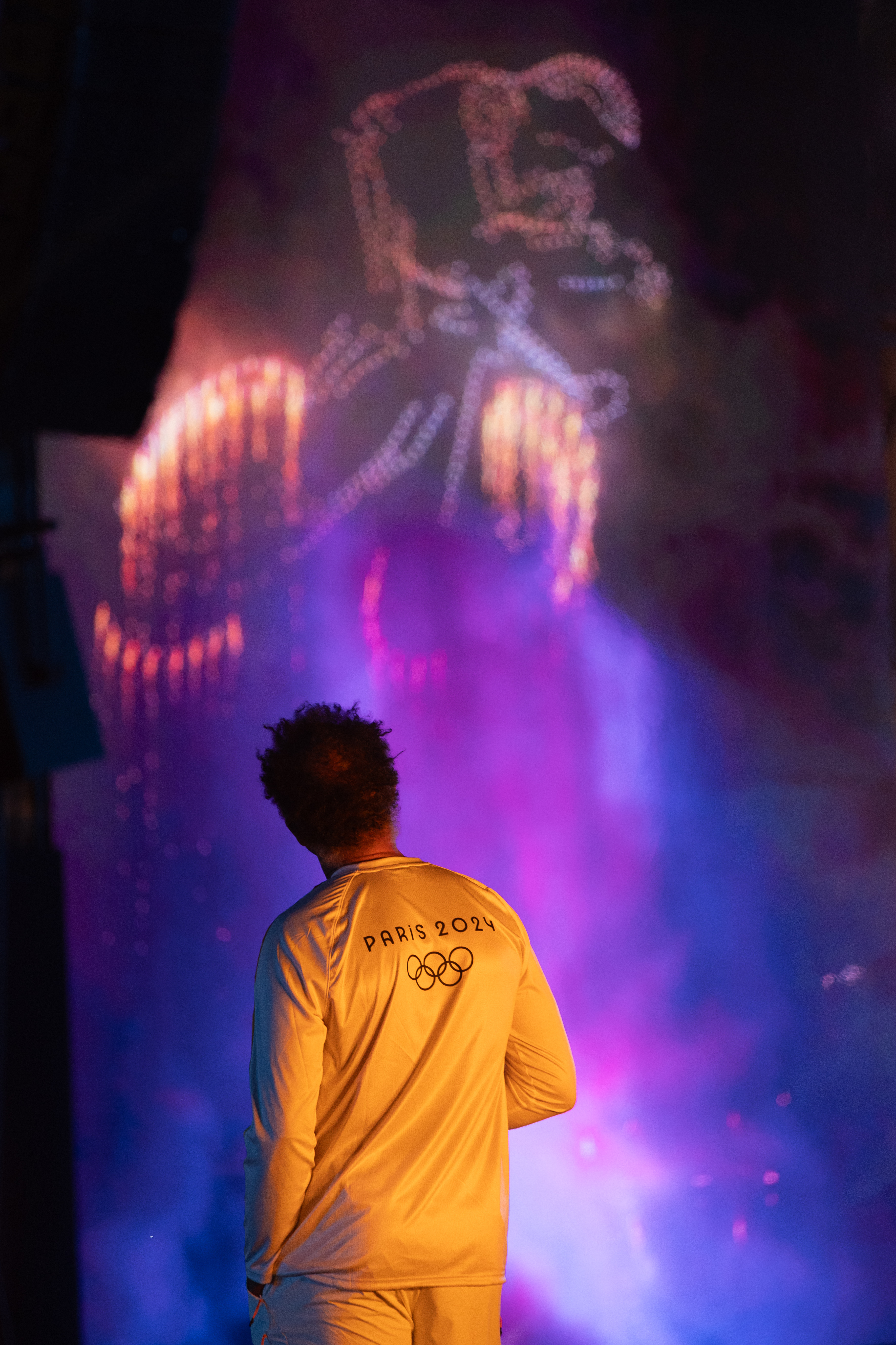 Juste après l'euphorie du passage de la flamme olympique le 14 juillet, Yannick Noah regarde tranquillement la projection du feu d'artifice.