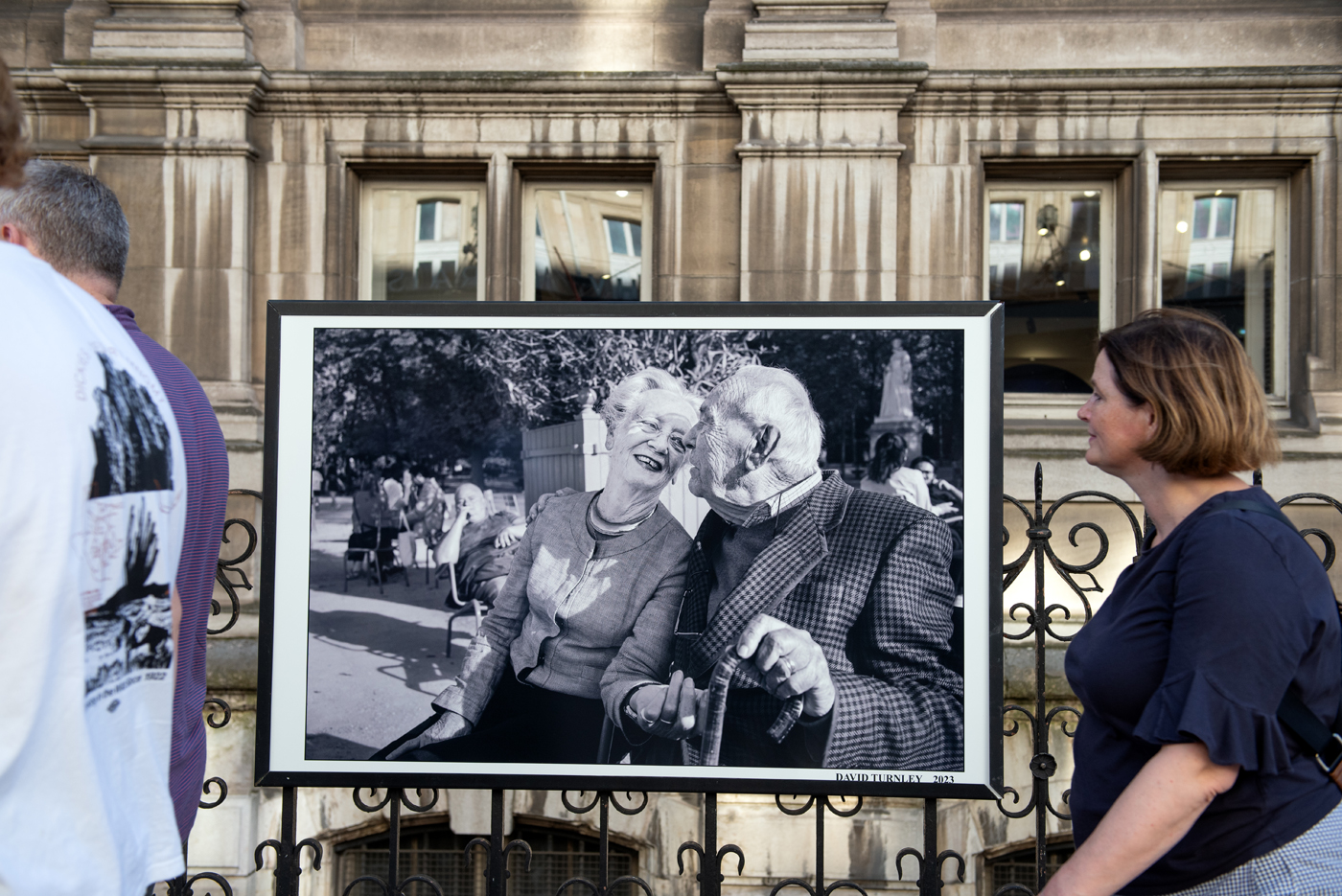 Des promeneurs passent devant une photographie de David Turnley lors  de son expo "Paris, l'Amour &amp; l'Espoir à l'HDV