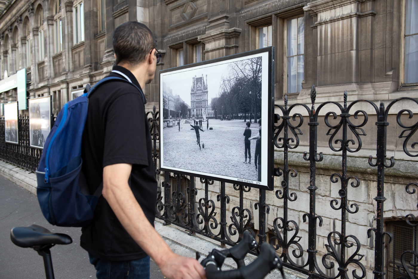 Un cycliste s'arrête devant une photographie de David Turnley lors  de son expo "Paris, l'Amour & l'Espoir à l'HDV