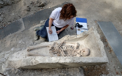 Une archéologue étudie une sépulture (squelette dans un sarcophage) découverte sur le site de l'Abbaye de Saint-Germain-des-Prés.