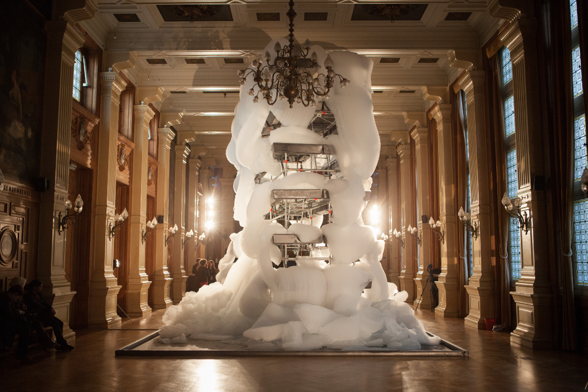  Bouquet Final 2, 2012. Installation par Michel Blazy à la Mairie du 4e. Cette installation, constituée d’une mousse blanche, épaisse et crémeuse, se déverse lentement et continuellement sur le sol. Ce débordement de matière célèbre avec humour un fantasme de rébellion des produits de supermarché contre la gabegie ambiante. 