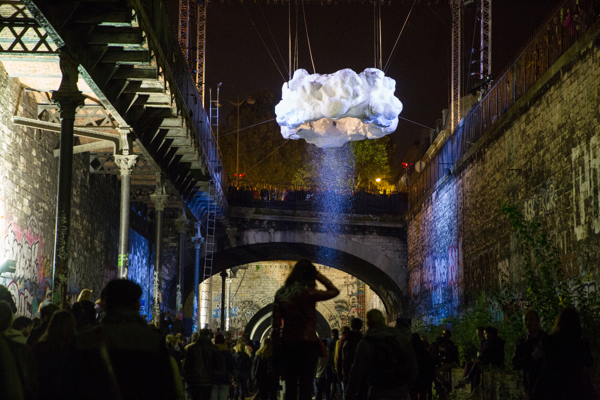 L'oeuvre Nuage - Installation et performance par Stéphane Ricordel à la Petite Ceinture (8e arr.). Dix mètres au-dessus du sol et des visiteurs, un homme saute dans un nuage. Provoquant le climat, il agit quelles qu’en soient les conséquences de la nature.