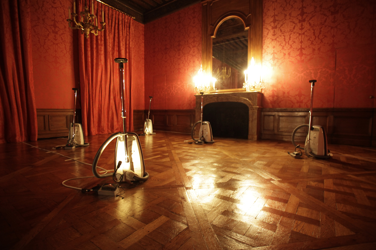 Harmonichaos - Une installation par Céleste Boursier-Mougenot à l’Hôtel de Lauzun (4e arr.). Dans la pénombre, un jeu de lumières met en avant les aspirateurs en tant qu’ « instruments », tandis que résonne une orchestration chromatique.