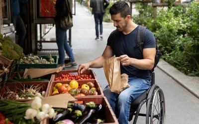 Un homme en fauteuil roulant fait ses courses au marché