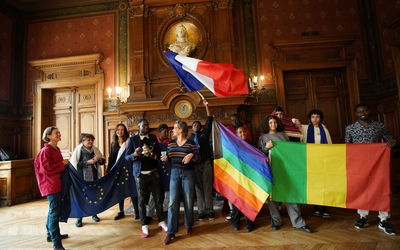 La maire du 14e accompagnée de l'artiste et de jeunes tenant des drapeaux représentant différentes communautés