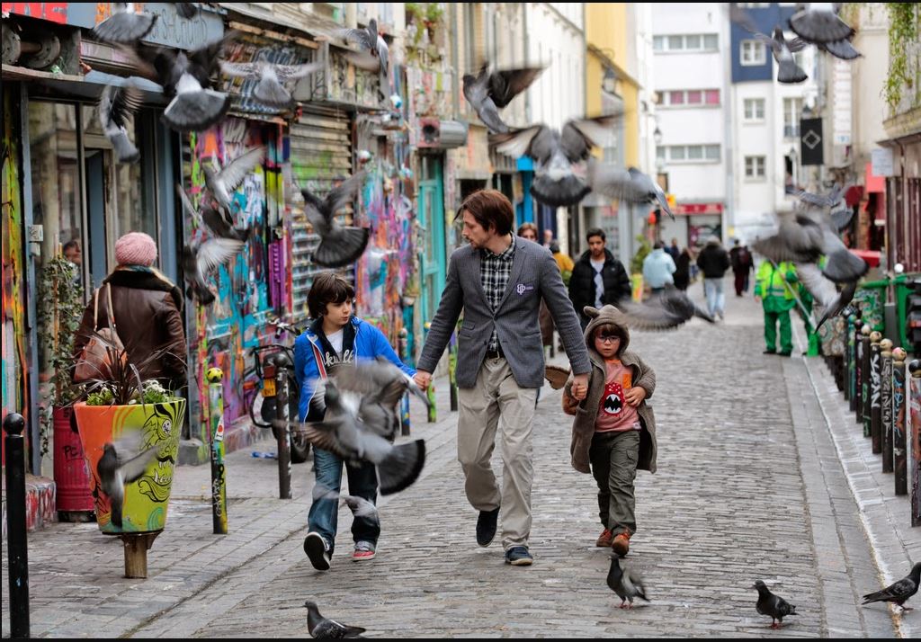 Des pigeons s'envolent sur le passage de trois personnages