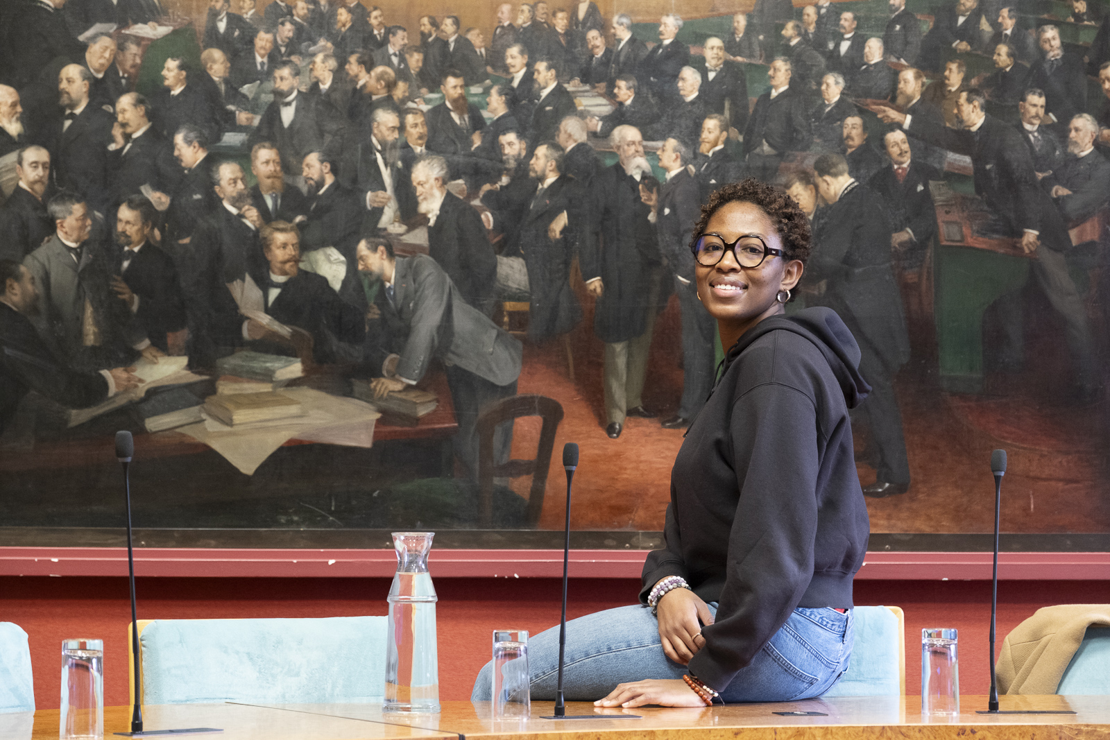 Solène Louber, membre du Conseil Parisien de la Jeunesse, pose devant une fresque d'élus parisiens, à l'Hôtel de Ville.