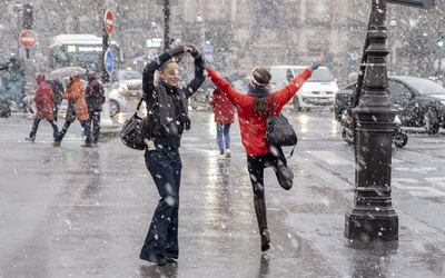 Des passantes dansent de joie sous la neige.