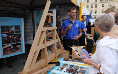 Le charpentier présente son travail devant une maquette de la charpente