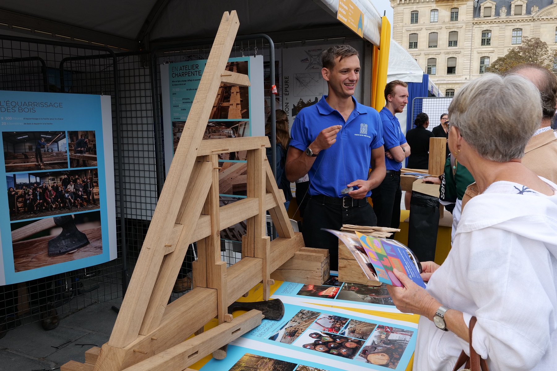 Le charpentier présente son travail devant une maquette de la charpente