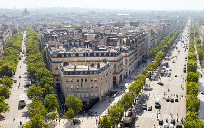 Vue d'un batiment sur deux avenues parisiennes arborées d'abres.