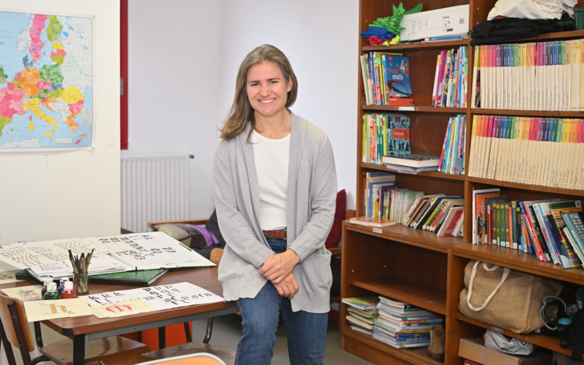 Fanny Armanet, adjointe éducative en collège pose dans son bureau entourée de livres et de dessins