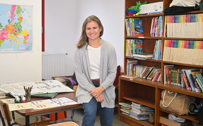 Fanny Armanet, adjointe éducative en collège pose dans son bureau entourée de livres et de dessins