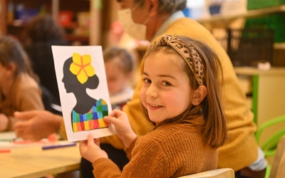 Une enfant souriante montre son coloriage