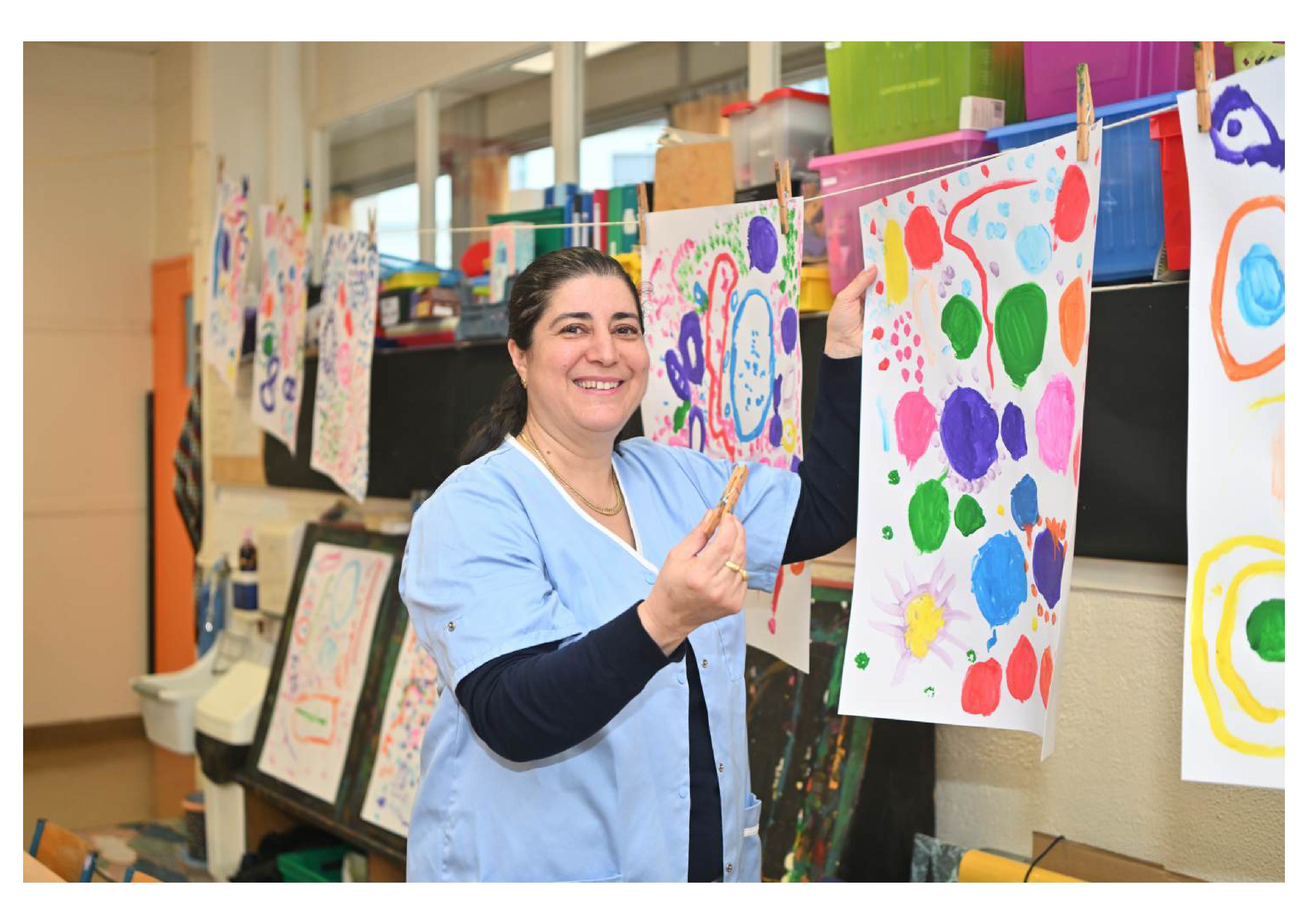 l'ASEM est en train d'accrocher des dessins d'enfants dans une classe