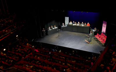 Sur une scène de théâtre, un faux procès avec au centre le jury, à gauche les avocats et à droite les témoins appelés à la barre.