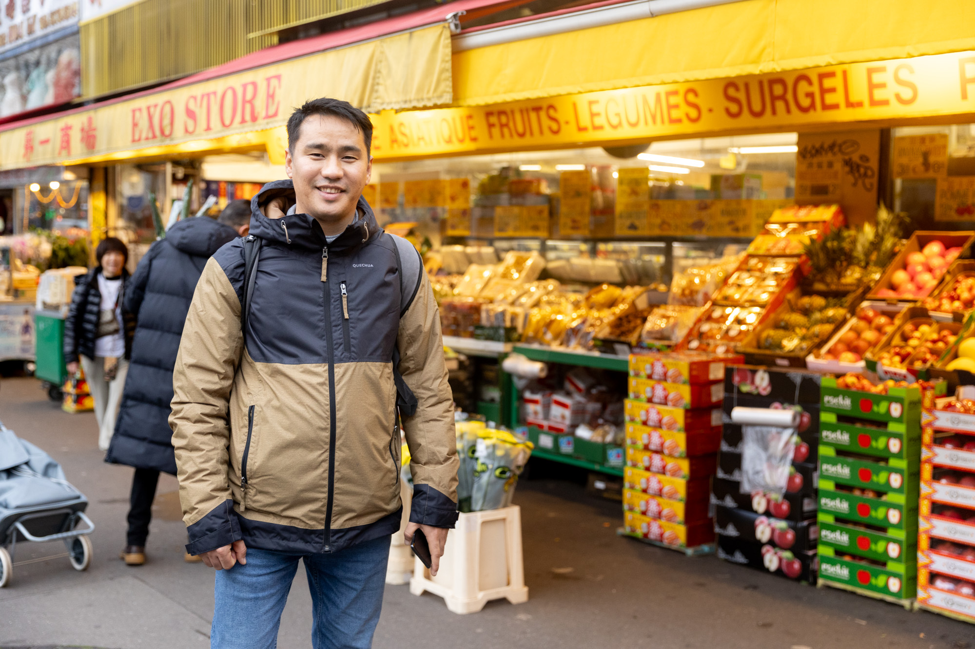 Portrait de Mortaza Rezaee devant des étales de marché dans le 13e arrondissement. 