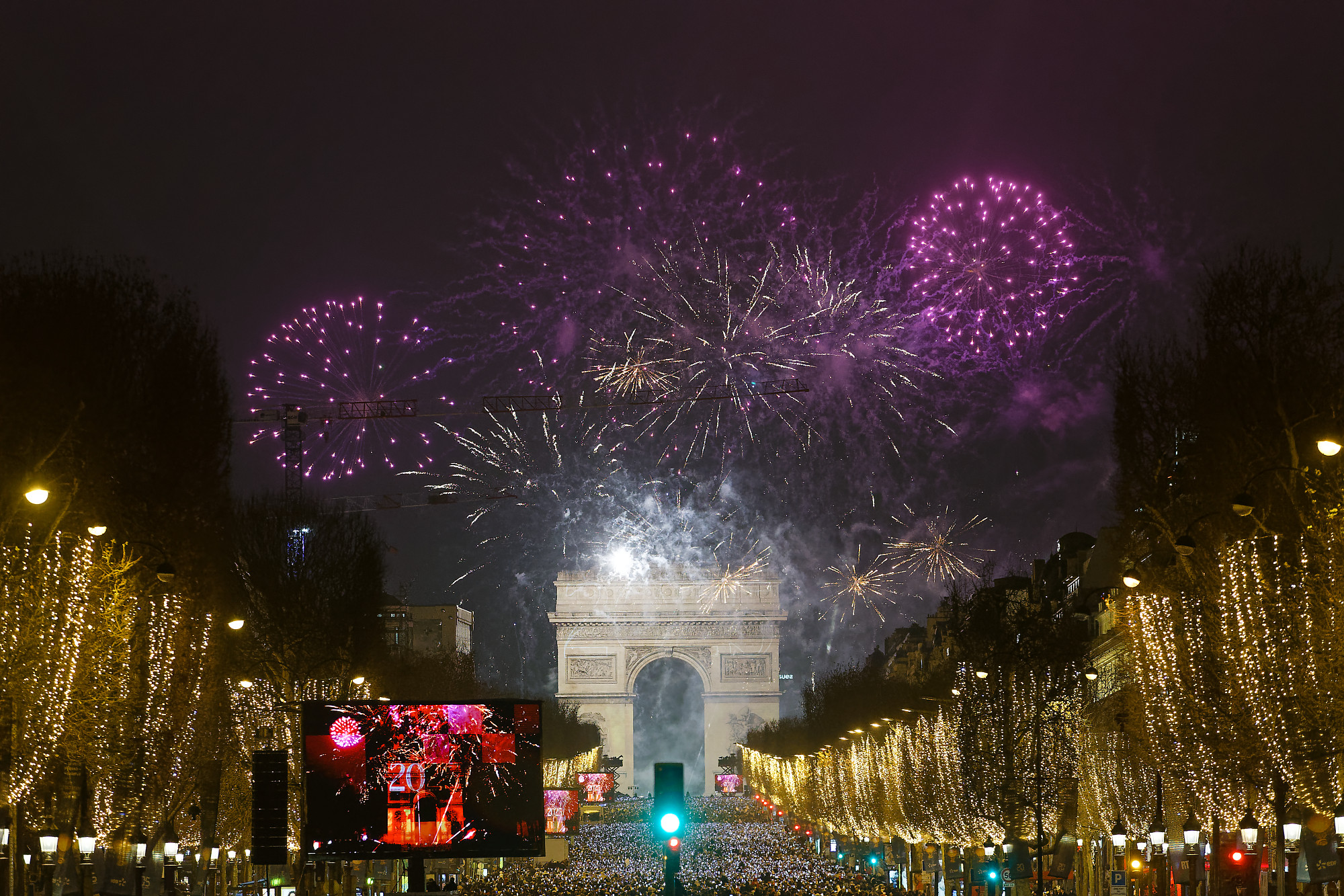 Vue large des Champs-Elysées illuminés par le feu d'artifice.