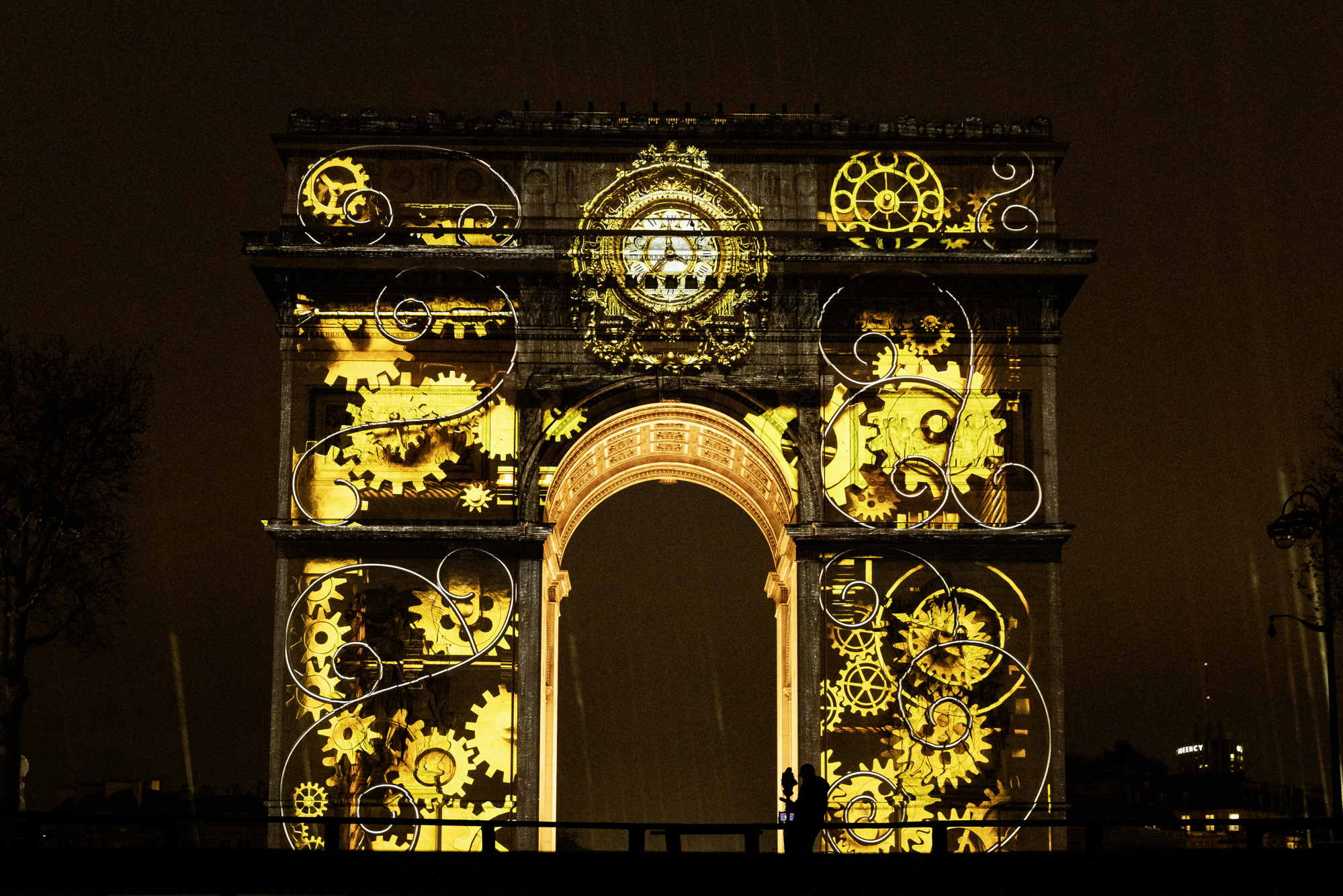 Collection de cadrans dorés projetée sur l'Arc de Triomphe.